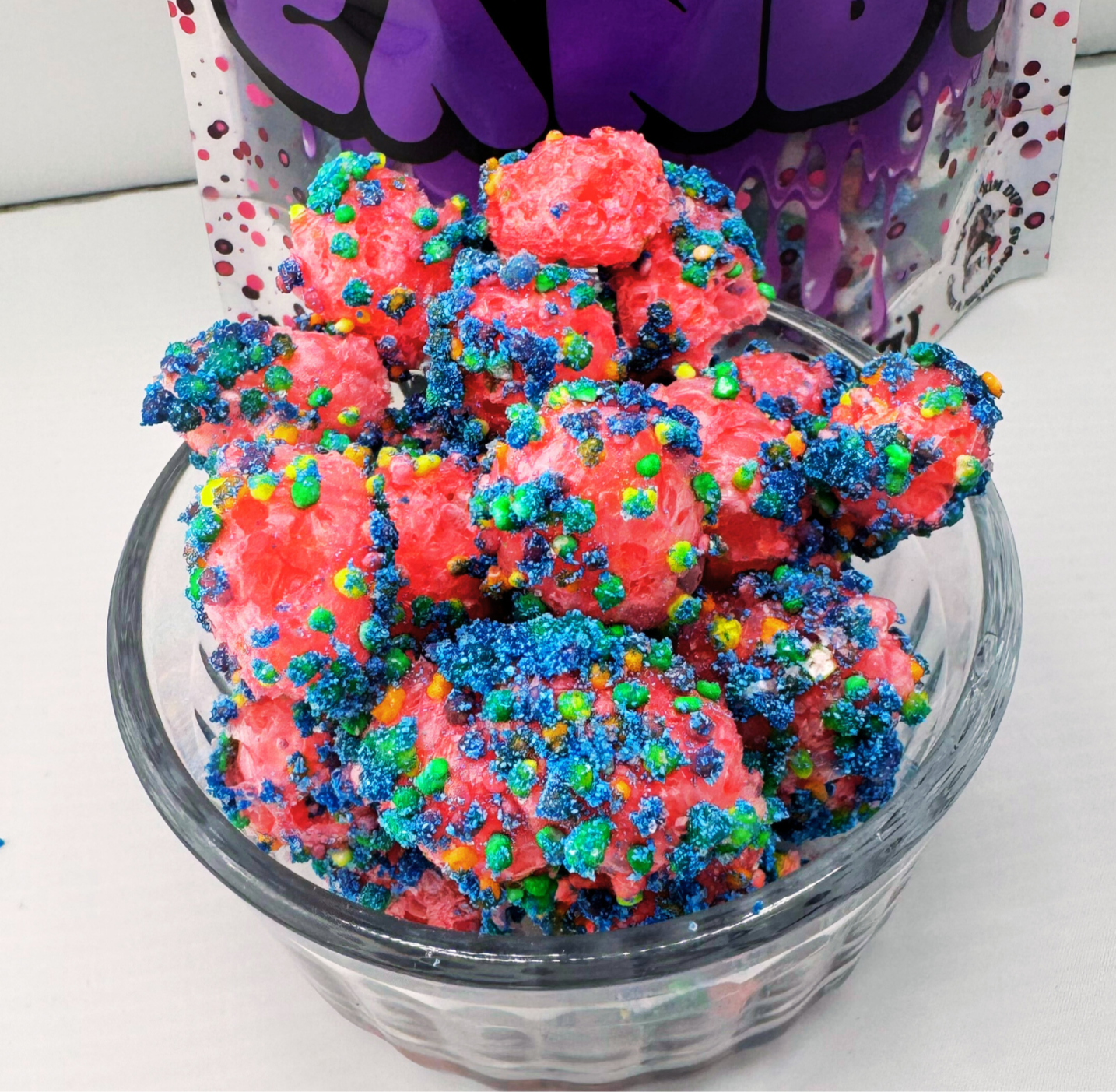 Colorful freeze-dried candy in a glass bowl with packaging in the background.