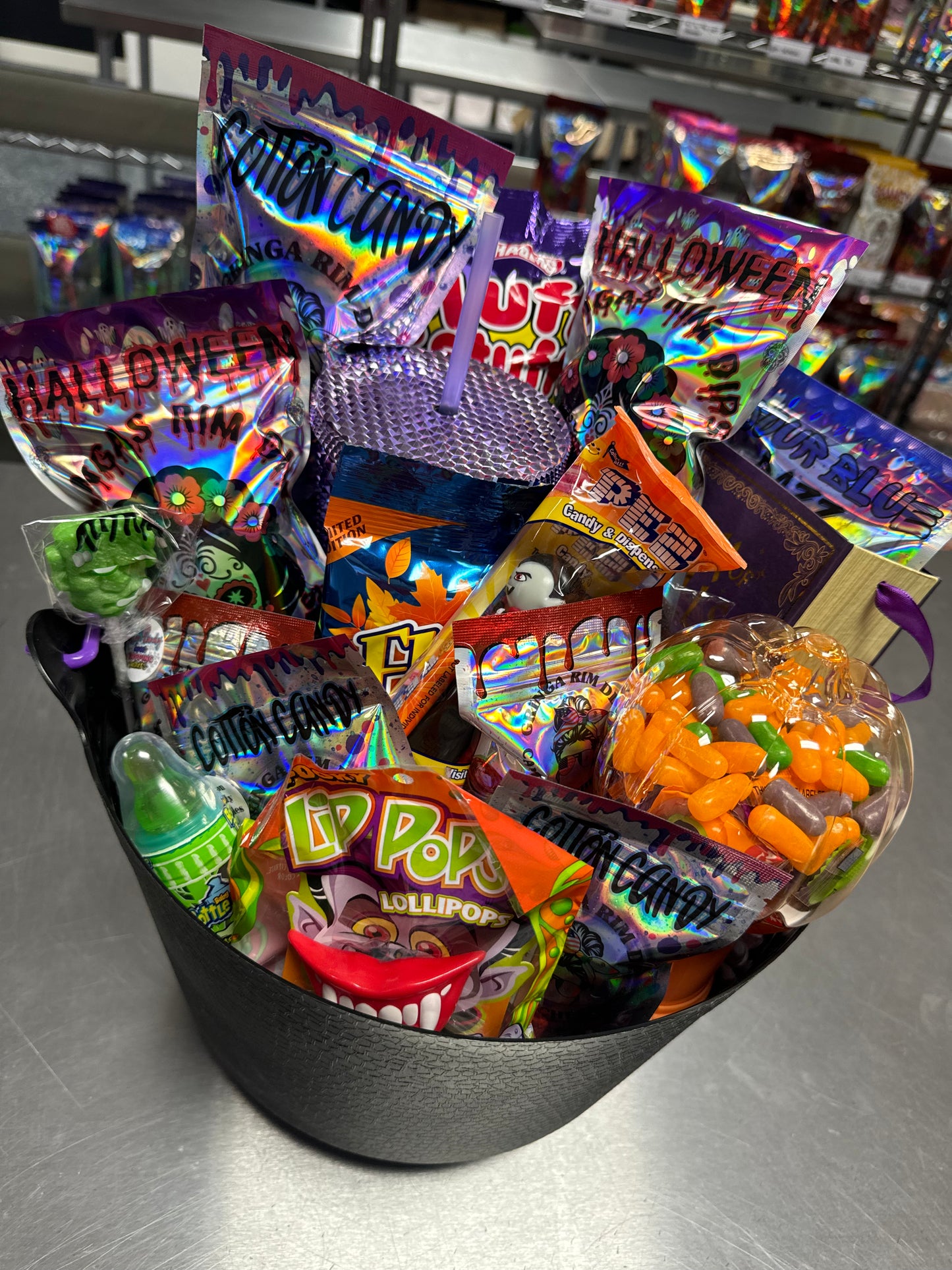 Halloween candy surprise buckets and totes filled with assorted spooky-themed candies, cotton candy, and mystery treats.