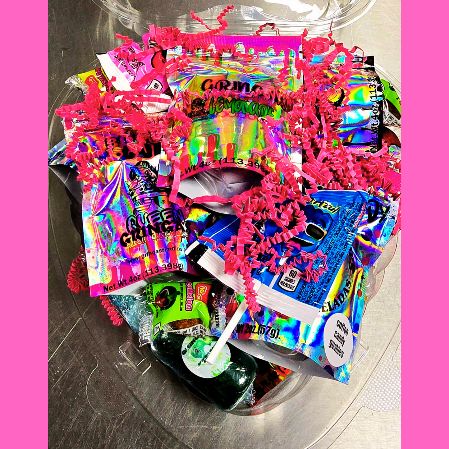 "Gringa’s Heart Candy Gift Box mockup featuring a clear heart-shaped container filled with assorted candies, pink shredded paper, and branded labels. Text reads 'Gringas Hearts – Candy That Says I Love You (or I Deserve This)' with a 'Limited Batches!' badge on a pink swirl background and Queen Gringa’s logo at the bottom."