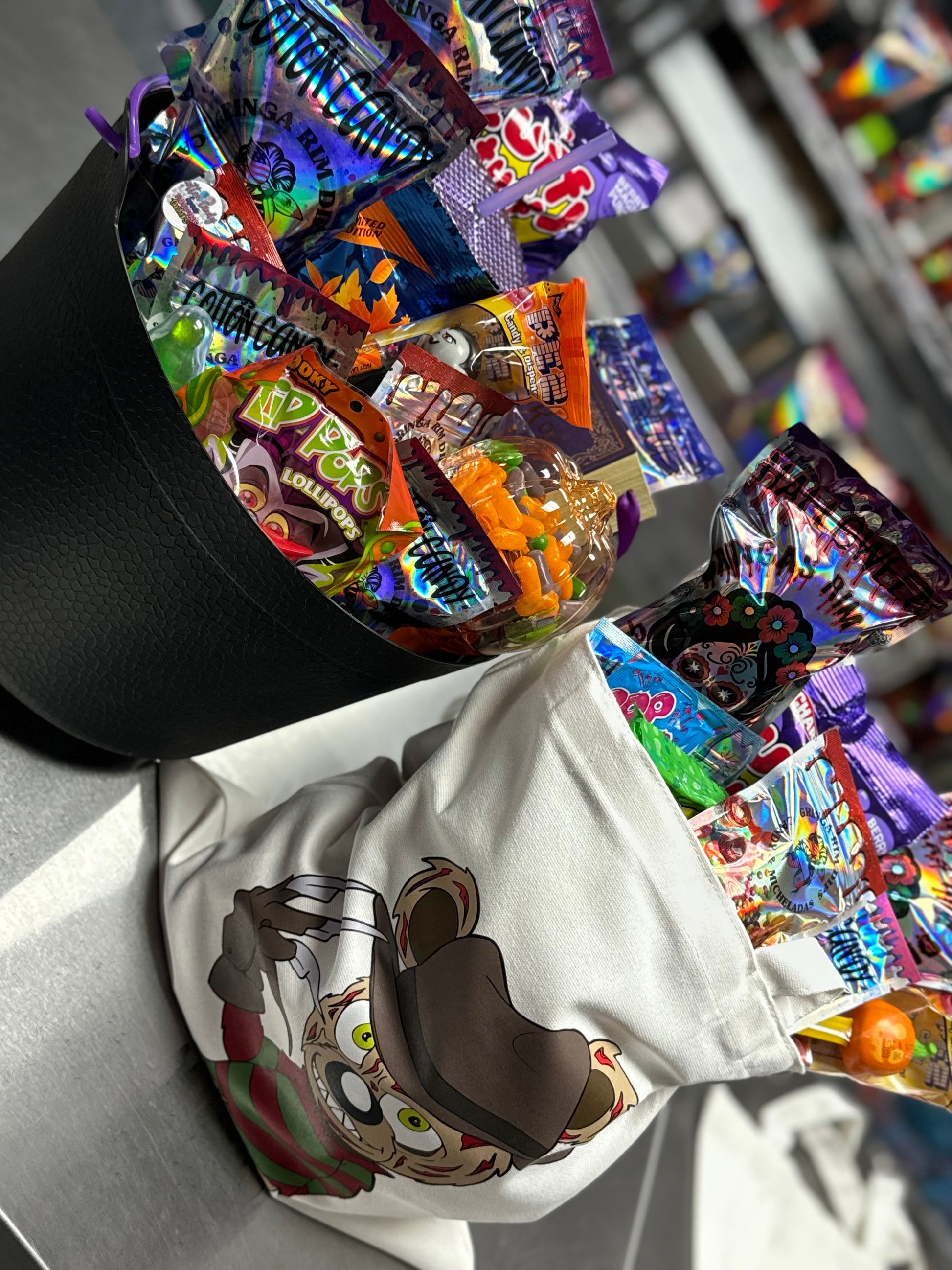 Halloween candy surprise buckets and totes filled with assorted spooky-themed candies, cotton candy, and mystery treats.