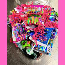 "Gringa’s Heart Candy Gift Box mockup featuring a clear heart-shaped container filled with assorted candies, pink shredded paper, and branded labels. Text reads 'Gringas Hearts – Candy That Says I Love You (or I Deserve This)' with a 'Limited Batches!' badge on a pink swirl background and Queen Gringa’s logo at the bottom."